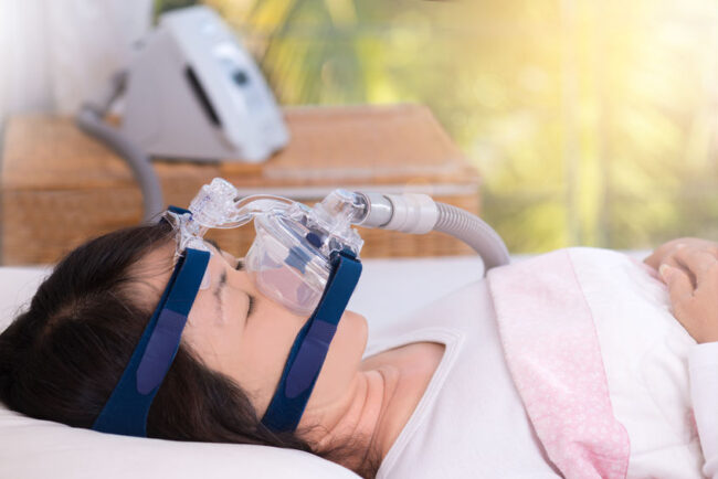 Obstructive sleep apnea therapy, Woman using CPAP machine.CPAP: