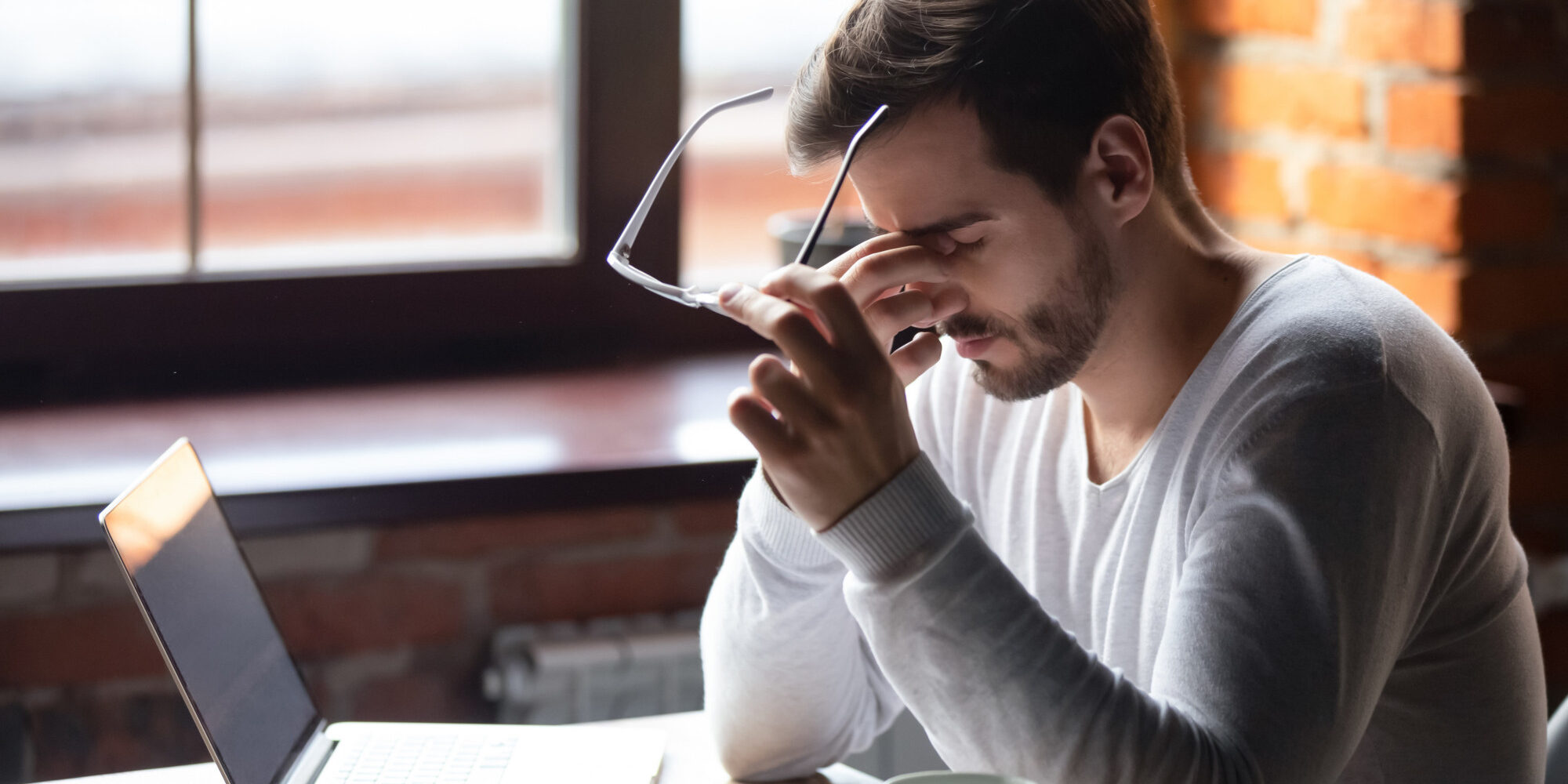 Upset man massaging nose bridge, taking off glasses, feeling eye strain